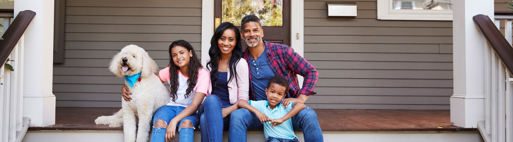 A family and their dog sitting on their front porch